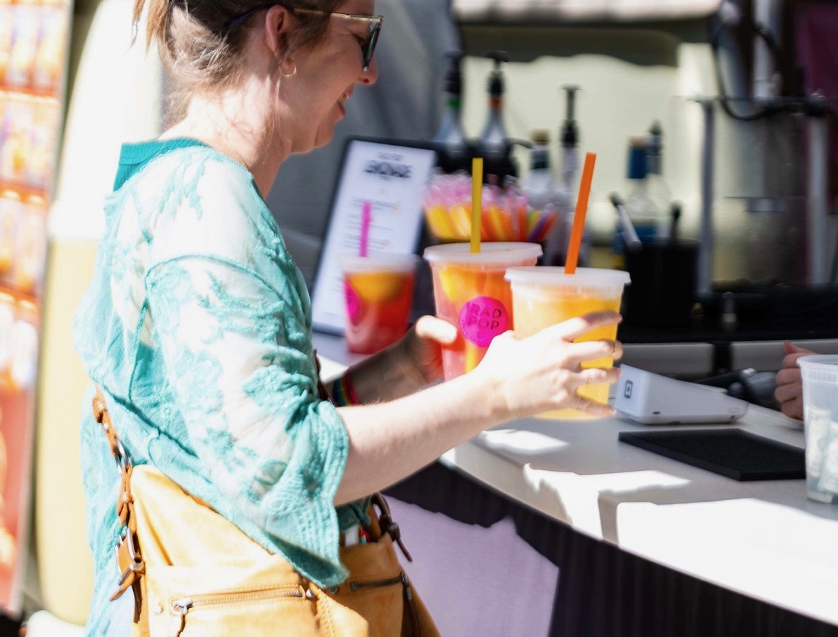 Customer carrying three Rad Pop drinks away from the booth