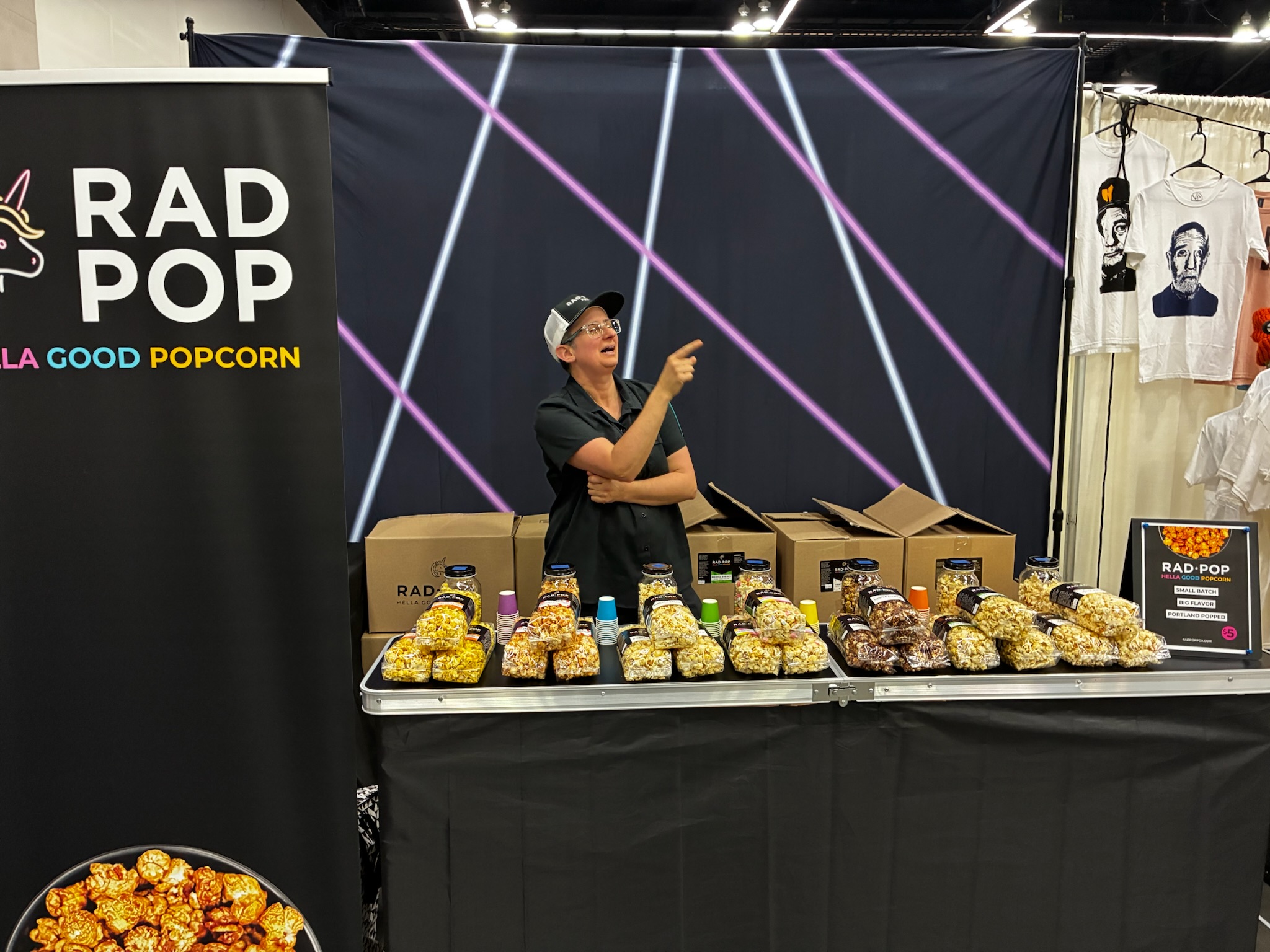 Rad Pop booth set up at an indoor expo with rows of popcorn bags and branded signage