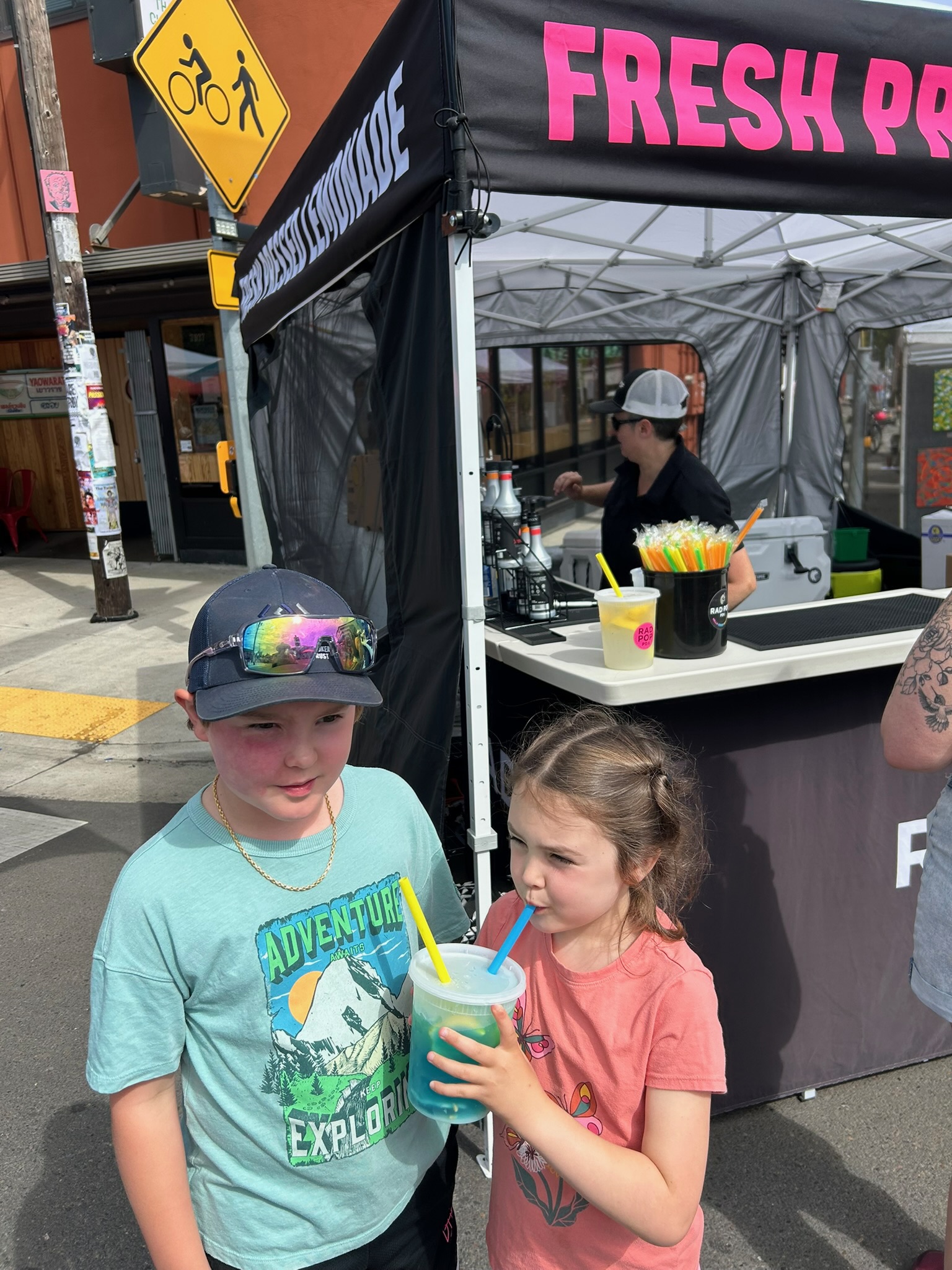 Two kids sharing a bright blue drink in front of the Rad Pop booth